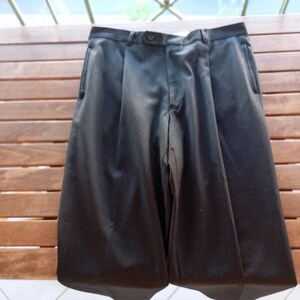 May include: A pair of solid black trousers featuring a structured waistband with a single centred button closure, a zipped fly, and two vertical side pockets. The fabric has a subtle sheen, and the legs are tailored with a clean, straight-leg cut.