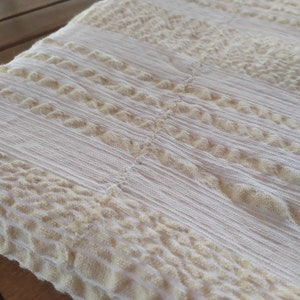 May include: White throw blanket with a textured, woven pattern. The blanket has a subtle, off-white color and a raised, textured design.