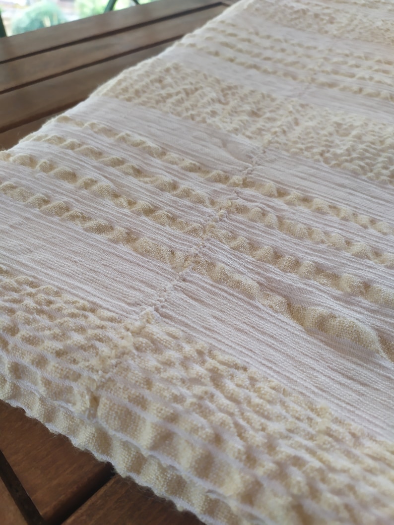 May include: White throw blanket with a textured, woven pattern. The blanket has a subtle, off-white color and a raised, textured design.