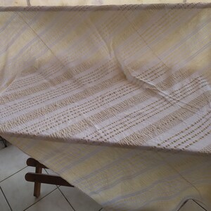 May include: White tablecloth with a yellow and white striped pattern. The tablecloth has a textured surface with small raised dots.