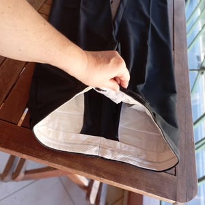 May include: A pair of black trousers featuring a high-waisted design with a white interior lining. The waistband is constructed with a light-coloured fabric, and the garment displays a clean, structured silhouette with visible seams along the waist.