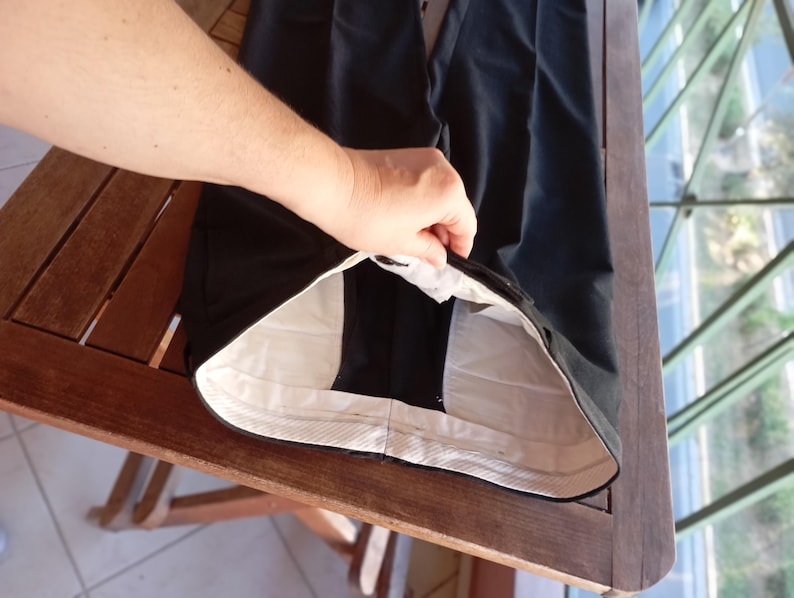 May include: A pair of black trousers featuring a high-waisted design with a white interior lining. The waistband is constructed with a light-coloured fabric, and the garment displays a clean, structured silhouette with visible seams along the waist.