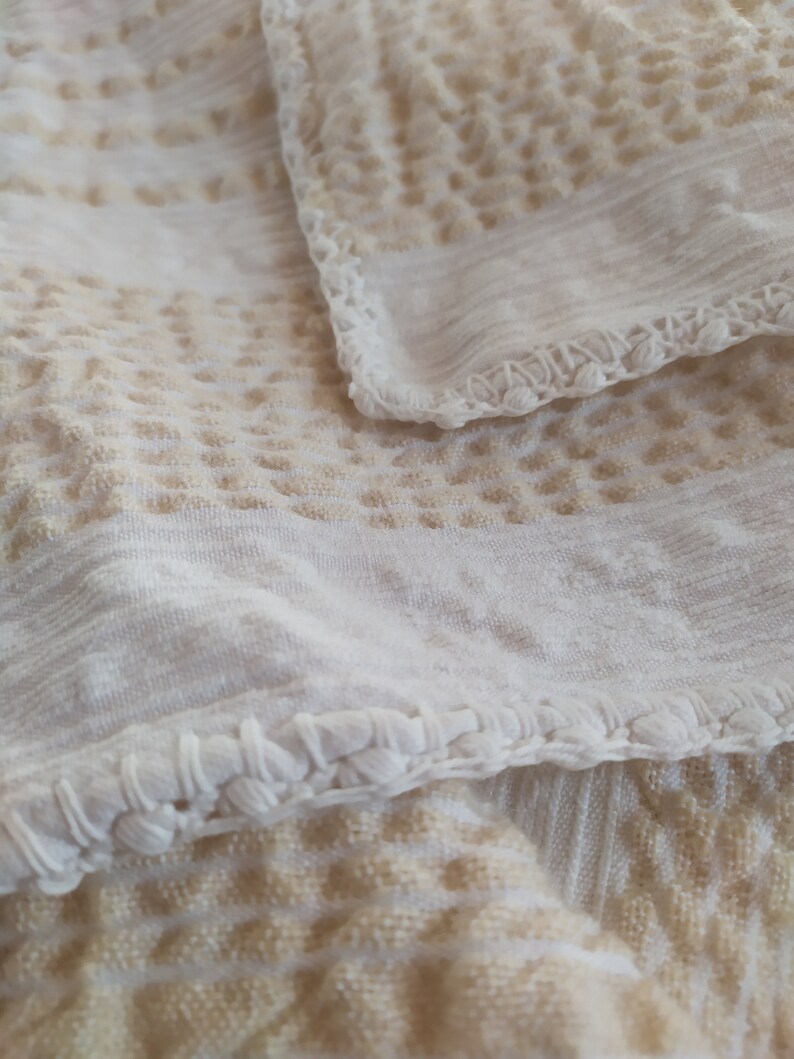 May include: White crocheted fabric with a textured pattern. The fabric has a delicate, lacy edge.