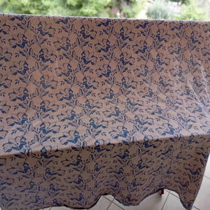 May include: A white fabric with a blue floral pattern. The fabric is folded and draped over a chair.