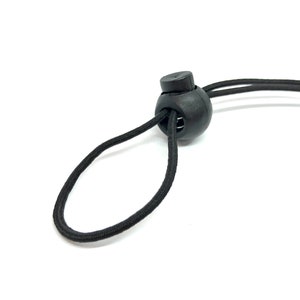 May include: Black elastic cord with a black plastic toggle. The cord is looped through the toggle.
