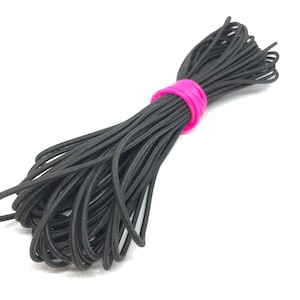 May include: A close-up of a black elastic cord, bundled and tied with a pink rubber band. The cord is a thin, flexible material, ideal for crafting or DIY projects.