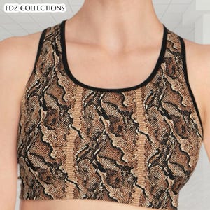Könnte beinhalten: Sport-BH mit Schlangenmuster in Braun-, Beige- und Schwarztönen. Der BH hat ein Racerback-Design mit schwarzem Besatz. Der Text "EDZ COLLECTIONS" ist oben links sichtbar.