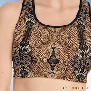 Puede incluir: Un sujetador deportivo marrón y negro con un estampado de piel de serpiente. El sujetador tiene cuello redondo y ribete negro. El texto "EDZ COLLECTIONS" está en la parte inferior de la imagen.