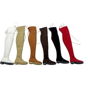 May include: A collection of six over-the-knee boots in various colors, including white, tan, brown, dark brown, black, and red. Each boot features a flat sole and a lace-up design at the top. The boots are displayed against a white background.