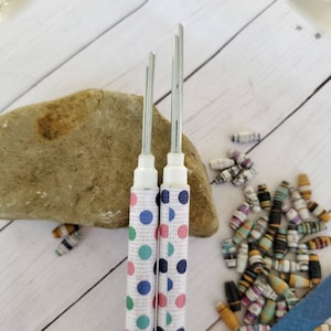 May include: Three white paper-wrapped tools with metal tips for rolling paper beads. The tools have different sized tips and are decorated with colourful polka dots.
