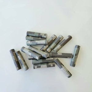 Peut inclure: Un tas de 14 tubes en papier brun et vert, peut-être pour rouler des cigarettes.