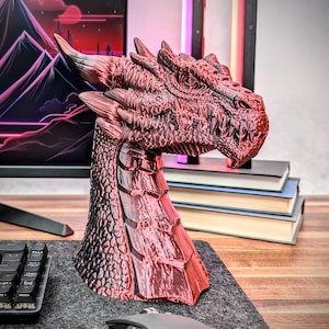 May include: A red and black dragon head sculpture with a detailed textured surface. The sculpture is made of a shiny material and has a fierce expression.
