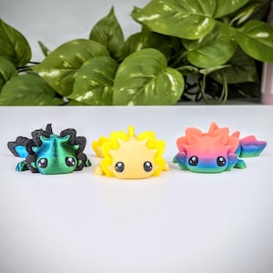 May include: Three small, 3D printed axolotl figurines. The axolotls are in different colors: green, yellow, and rainbow.