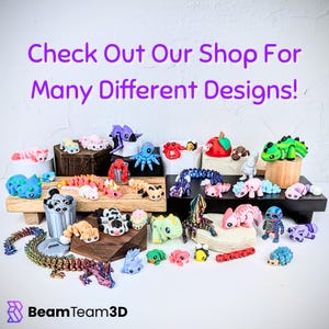 May include: A collection of colorful 3D-printed figurines, including dragons, axolotls, and other creatures, displayed on wooden platforms and white surfaces. The text "Check Out Our Shop For Many Different Designs!" is visible.