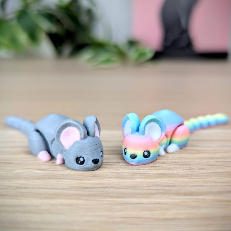 May include: Two small, hand-painted mouse figurines. One is gray with pink ears and the other is rainbow colored with a white belly.