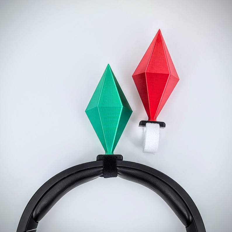 May include: A black headband with two colorful diamond-shaped charms attached. The charms are red and green.