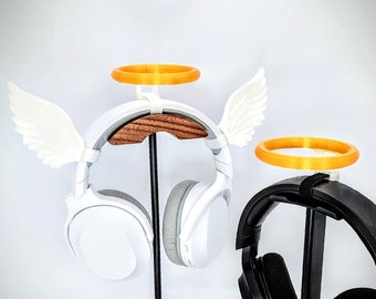 May include: Two headphone stands, one white with a halo and wings, the other black with a halo. Both stands are holding headphones.