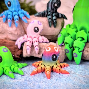 May include: A collection of colorful octopus figurines with articulated limbs. The octopus figurines are made of plastic and have a variety of colors, including blue, pink, green, and rainbow.