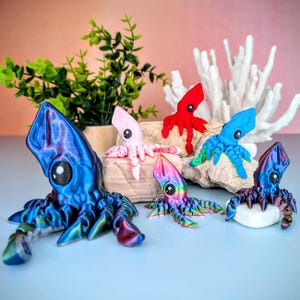 May include: Five colorful hand-painted squid figurines, each with a unique design and color. The squid are made of a smooth, glossy material and have realistic details, including large eyes and tentacles. The squid are arranged on a wooden surface with a white coral background.