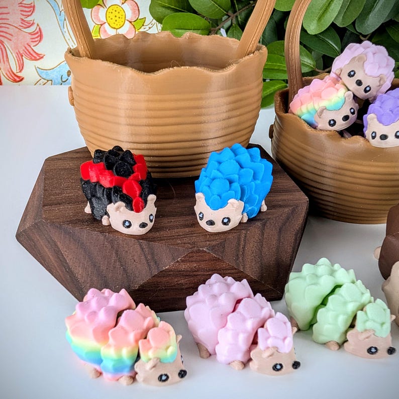 May include: A collection of colourful, hand-painted hedgehog figurines. The hedgehogs are made of a smooth, ceramic-like material and have a variety of colours and patterns. They are arranged on a wooden surface.