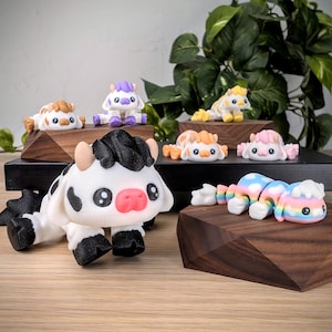May include: A collection of small, hand-painted figurines of cows in various colors and patterns. The figurines are displayed on wooden bases.