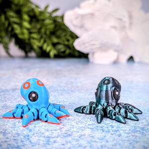 May include: Two small octopus figurines, one blue with orange accents and the other dark green with a metallic sheen.
