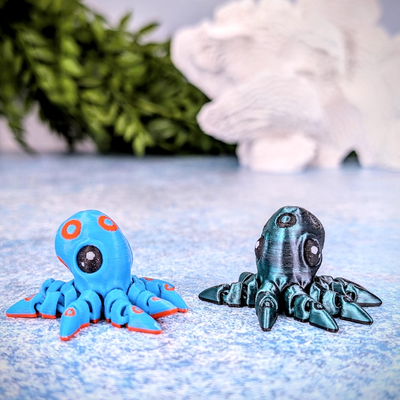 May include: Two small octopus figurines, one blue with orange accents and the other dark green with a metallic sheen.