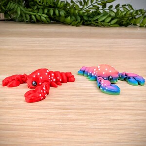 May include: Two small lobster figurines, one red with white dots and the other with a rainbow gradient and white dots.
