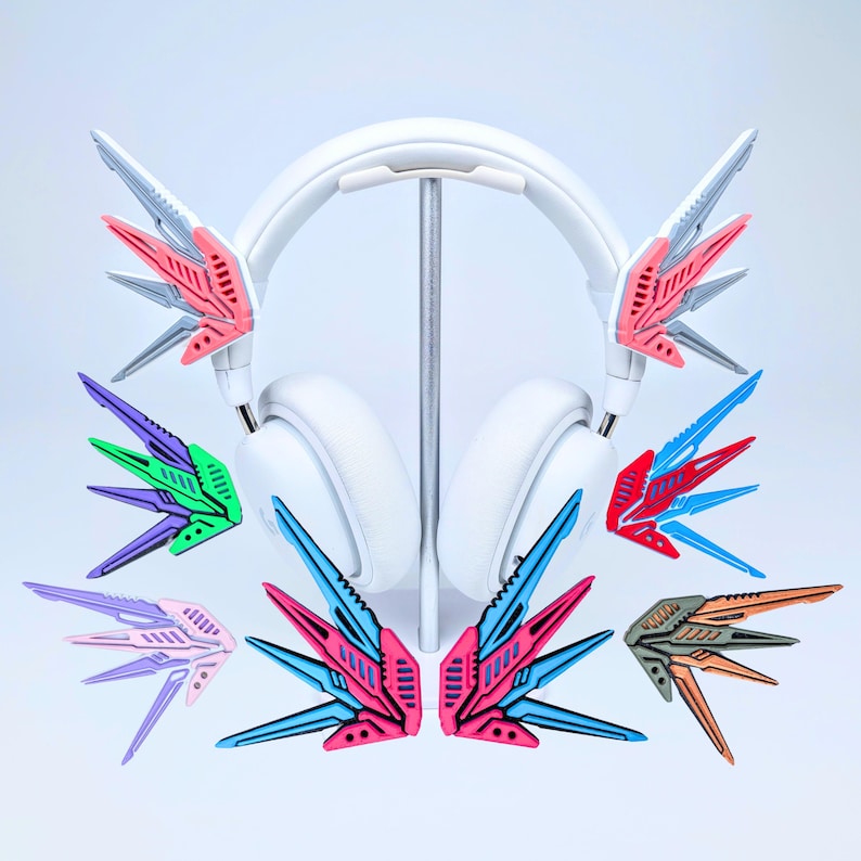 May include: White headphones with colorful, wing-shaped attachments in various colors, including pink, blue, green, and orange. The attachments have a geometric design and are displayed with the headphones on a stand.