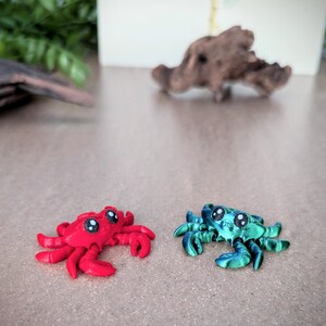 May include: Two small, hand-painted, ceramic crabs. One crab is red with black eyes and the other is green with black eyes.
