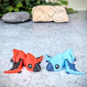 May include: Two small, hand-painted figurines of mythical creatures. One is red with black wings and the other is blue with dark blue wings.