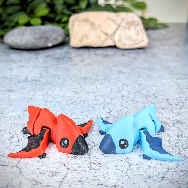 May include: Two small, hand-painted figurines of mythical creatures. One is red with black wings and the other is blue with dark blue wings.