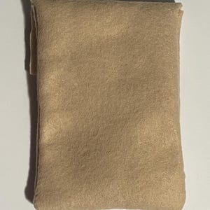Puede incluir: Una funda rectangular y plegada de fieltro color beige. La funda est&aacute; hecha de un material suave y texturizado y parece estar vac&iacute;a. Los bordes est&aacute;n cuidadosamente cosidos y el dise&ntilde;o es simple y minimalista.