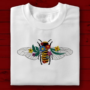 Op de afbeelding: Wit T-shirt met een geborduurd bijendesign. De bij is omringd door kleurrijke bloemen en heeft een geel-zwart gestreept lichaam.