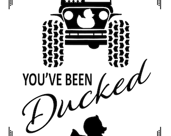 Może przedstawiać: Czarno-biała ilustracja jeepa z amerykańską flagą na masce i gumową kaczką w przedniej szybie. Tekst "You've Been Ducked" jest napisany stylizowanym fontem pod jeepem. Gumowa kaczka jest również przedstawiona na dole obrazu.