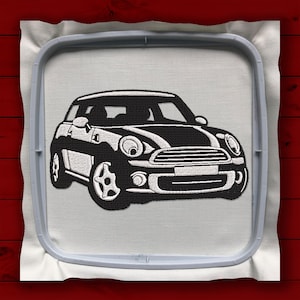 Op de afbeelding: Zwart-wit geborduurd ontwerp van een Mini Cooper op een witte stoffen achtergrond.