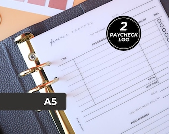 Puede incluir: Planificador de seguimiento financiero tamaño A5 con anillos dorados. El planificador está abierto en una página etiquetada como "Paycheck Log" con espacios para fechas, importes y gastos. El planificador es gris.