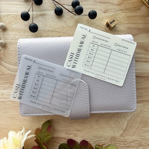 May include: Two white cash withdrawal trackers with a grid for recording bills and amounts. The trackers are labeled "Cash Withdrawal" and have the text "Thank you and have a great day!" at the bottom.