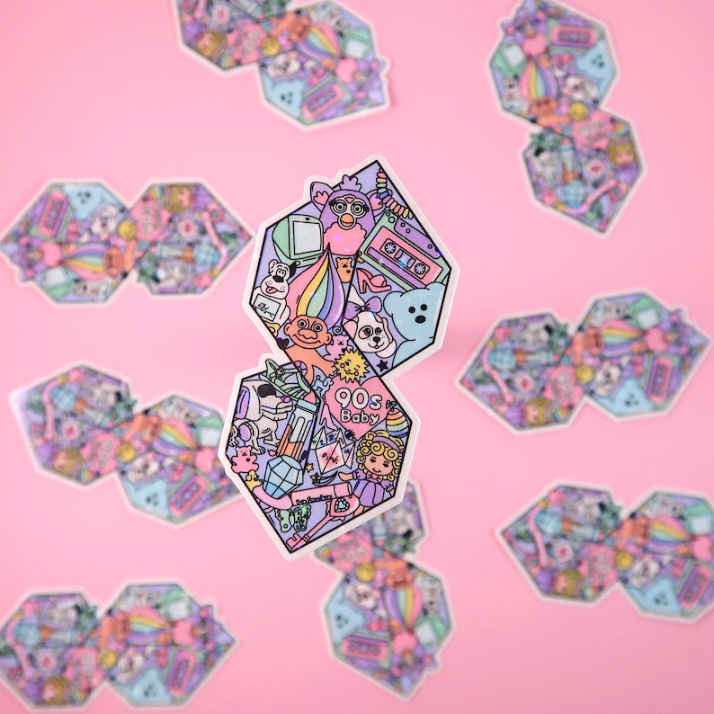Pu&ograve; includere: Un adesivo con uno schema di colori rosa, blu e giallo che presenta una variet&agrave; di icone della cultura pop degli anni '90, tra cui una bambola troll, un Furby, un nastro per cassette e un arcobaleno. L'adesivo dice "90s Baby" al centro.