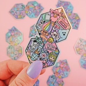 Pu&ograve; includere: Due adesivi esagonali a tema anni '90. L'adesivo superiore presenta un troll con i capelli arcobaleno, una creatura rosa e pelosa, un nastro per cassette, un tacco alto e un orsacchiotto di peluche. L'adesivo inferiore presenta un bambino dei cartoni animati, un arcobaleno, un cristallo e un cuore rosa con il testo "90s Baby".
