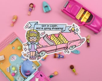 Puede incluir: Un coche de dibujos animados rosa y amarillo con un personaje femenino de dibujos animados de pie junto a él. El coche tiene una pancarta que dice "Get in Loser, we're going shopping!" La imagen está sobre un fondo rosa.