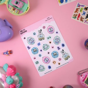 May include: A sticker sheet with illustrations of 90s virtual pets, including a dog and digital pet designs in pastel colours. The stickers have the text "MISS FITZ ILLUSTRATION" and "5408 90s Virtual Pets". Other 90s toys are visible in the background.