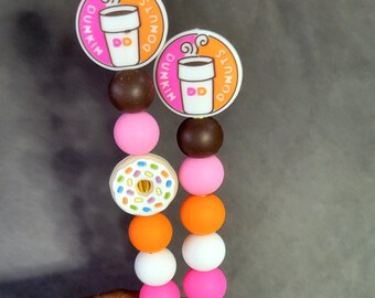 May include: Two colorful beaded bracelets with donut and coffee cup charms. The charms feature the Dunkin' Donuts logo. The beads are pink, orange, white, brown, and a donut-shaped bead with colorful sprinkles.