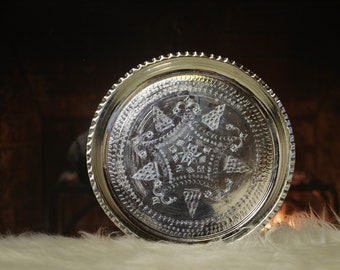 Puede incluir: Una bandeja de plata con un intrincado diseño en forma de estrella grabado en la superficie. La bandeja tiene un borde elevado y un borde perlado.