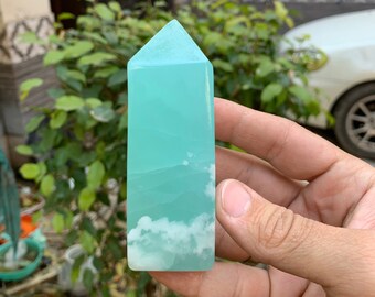 May include: A light blue and white crystal point with a cloudy pattern. The crystal is shaped like a pyramid with a pointed top.