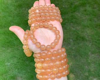 Può includere: Un mucchio di braccialetti di pietre preziose arancioni con perline rotonde.