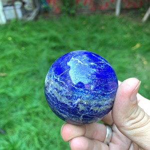 May include: A smooth, blue lapis lazuli sphere with white and gold veins. The sphere is polished and has a glossy finish.