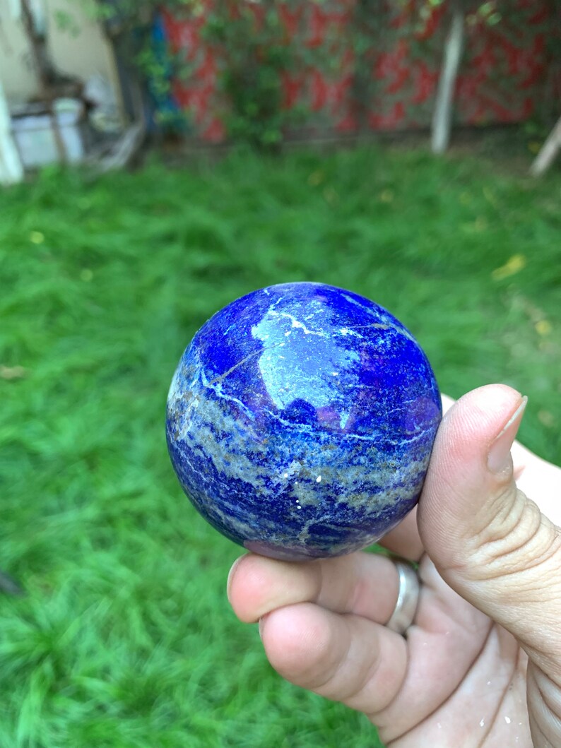 May include: A smooth, blue lapis lazuli sphere with white and gold veins. The sphere is polished and has a glossy finish.