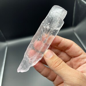May include: A translucent white selenite crystal wand with a smooth, polished surface. The wand has a natural, raw edge and is approximately 5 inches long.