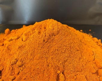 May include: A close-up of a pile of bright orange powder. The powder is finely ground and has a slightly rough texture.